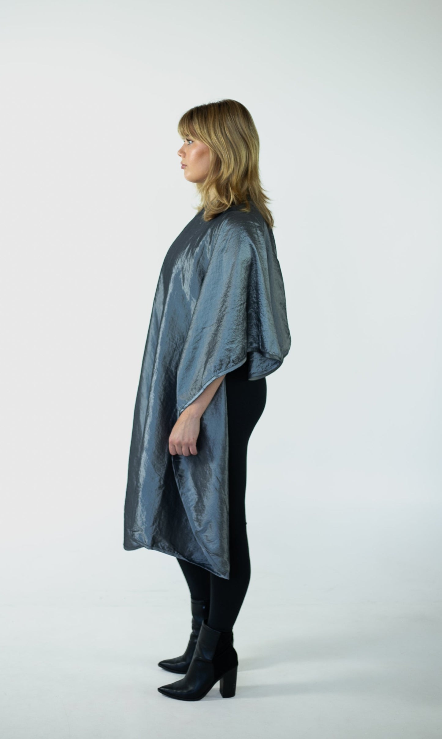  A woman is elegantly dressed in a grey poncho