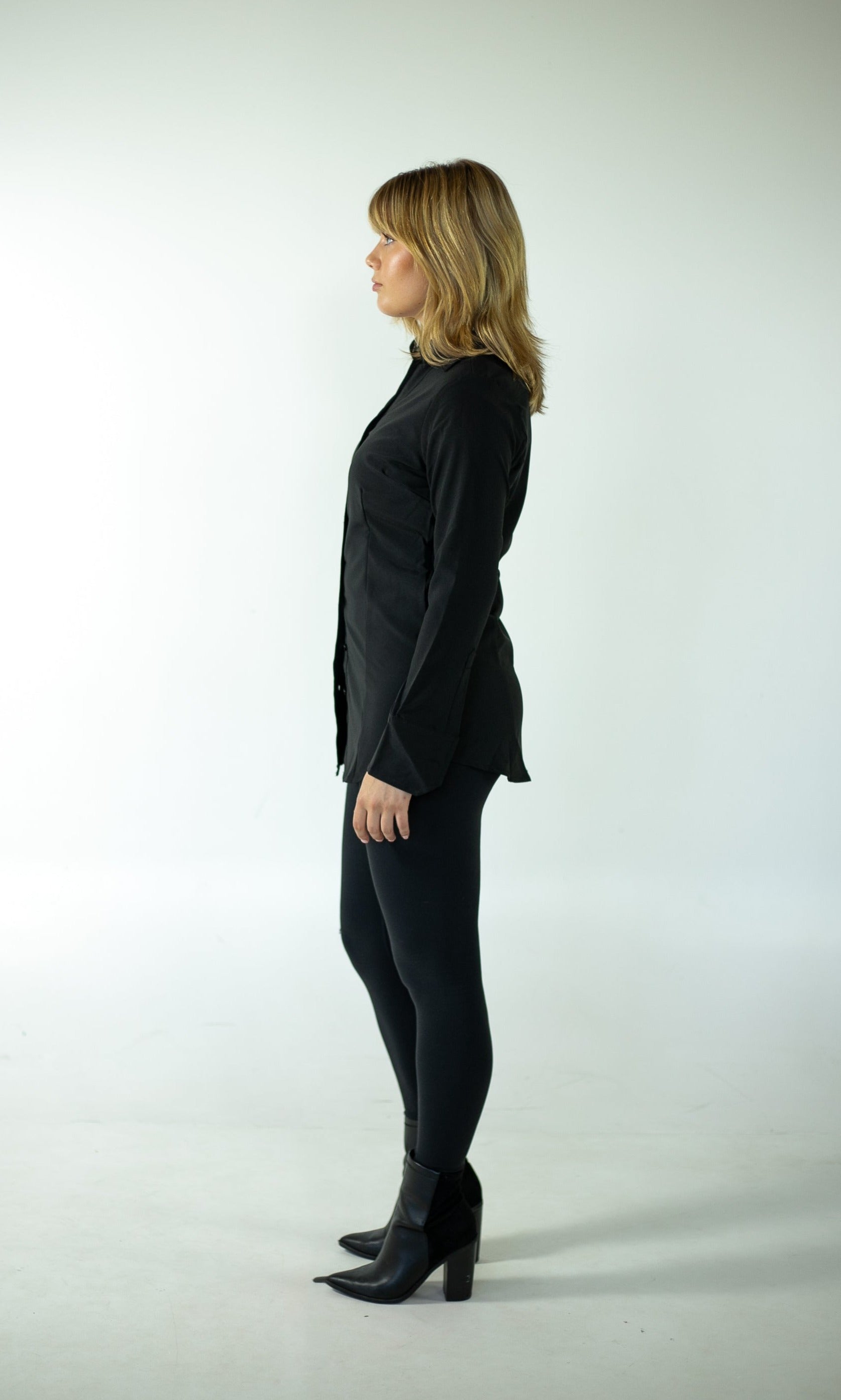 A woman wearing a black shirt and black pants poses