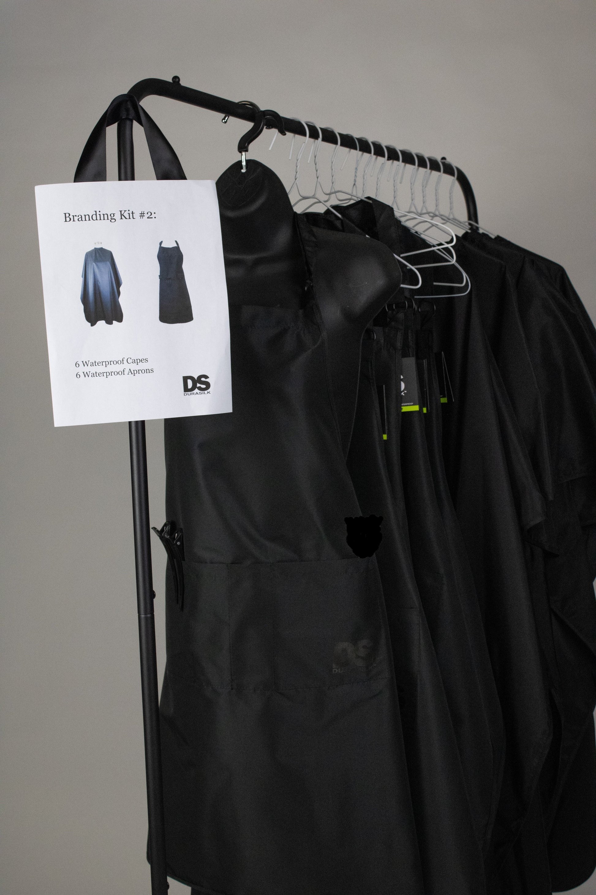 A black apron hanging on a hanger with a black shirt